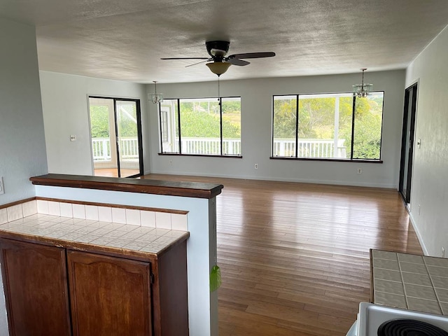 kitchen featuring tile countertops, hardwood / wood-style flooring, and ceiling fan with notable chandelier