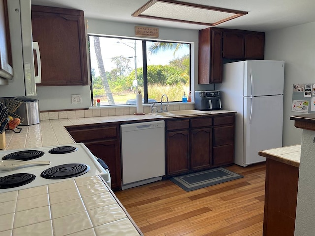 kitchen with sink, light hardwood / wood-style floors, tile counters, white appliances, and dark brown cabinetry