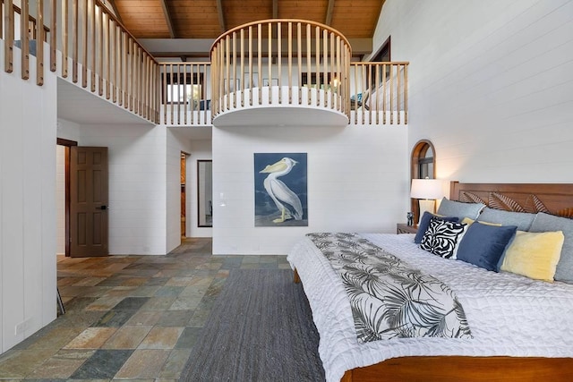 unfurnished bedroom featuring a towering ceiling, wood ceiling, stone tile floors, and beam ceiling