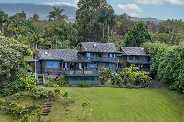 back of property featuring a yard, a standing seam roof, metal roof, and stairs