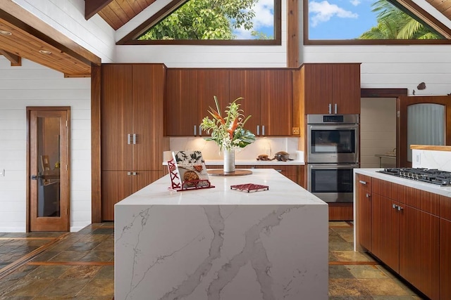 kitchen with stainless steel appliances, a kitchen island, stone tile flooring, and wooden walls