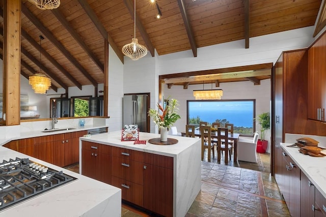 kitchen featuring stainless steel appliances, stone tile flooring, a chandelier, and a sink