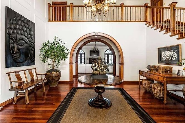 interior space featuring an inviting chandelier, dark hardwood / wood-style floors, and a towering ceiling