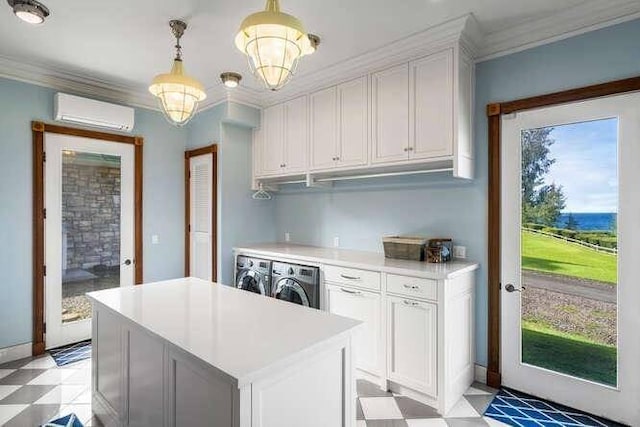 kitchen featuring a wall mounted AC, decorative light fixtures, light tile floors, washing machine and dryer, and white cabinets