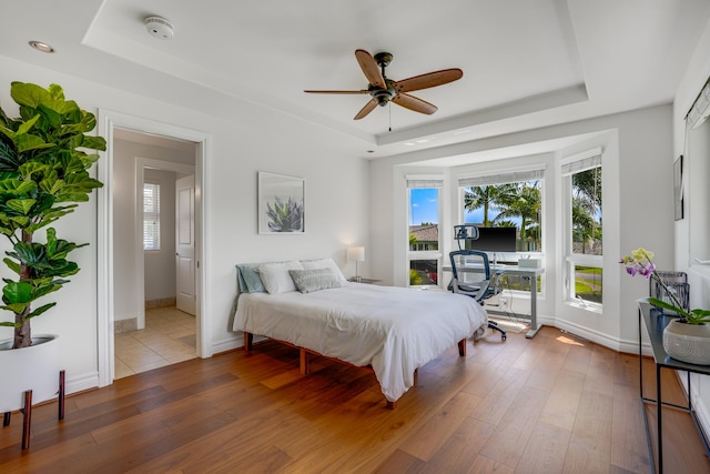 bedroom featuring hardwood / wood-style flooring, ceiling fan, and a tray ceiling