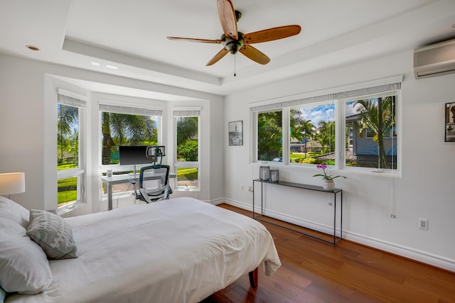 bedroom featuring a tray ceiling, ceiling fan, hardwood / wood-style floors, and an AC wall unit