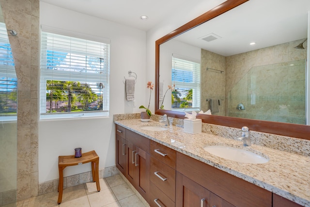 bathroom with tile patterned floors, vanity, a healthy amount of sunlight, and tiled shower