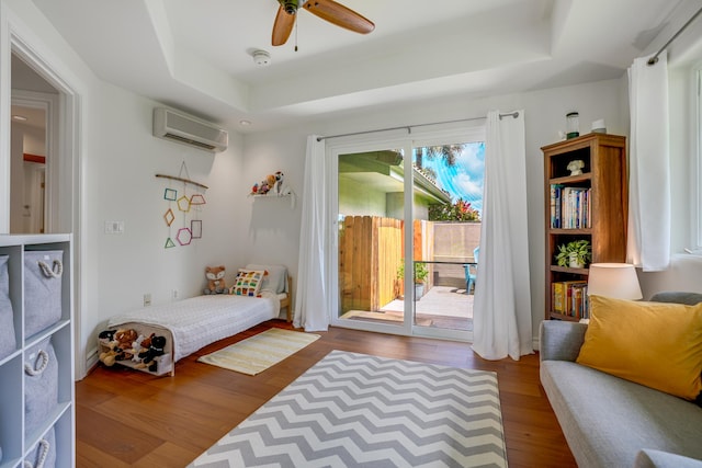 bedroom with access to exterior, hardwood / wood-style flooring, a wall unit AC, and multiple windows