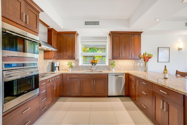 kitchen with kitchen peninsula, decorative backsplash, light stone countertops, and appliances with stainless steel finishes