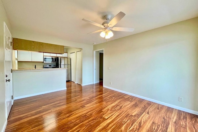 kitchen featuring kitchen peninsula, stainless steel appliances, ceiling fan, dark hardwood / wood-style floors, and white cabinets