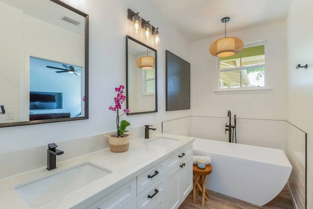 bathroom with a washtub, wood-type flooring, vanity, and ceiling fan