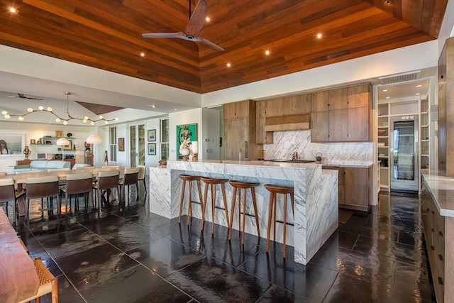 kitchen with backsplash, ceiling fan, wooden ceiling, and a large island