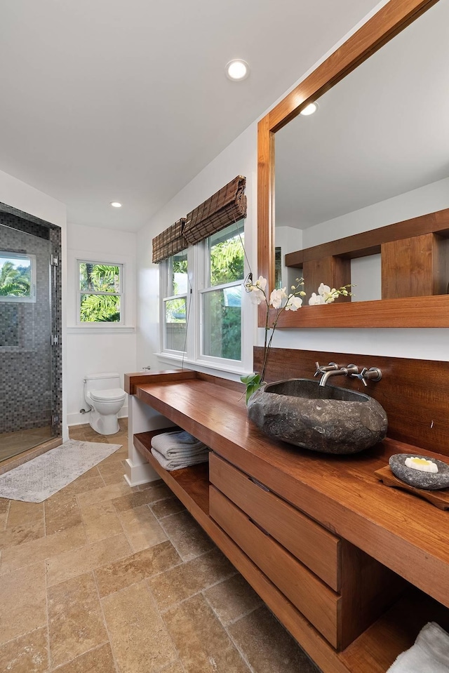 bathroom with a shower with door, vanity, and toilet