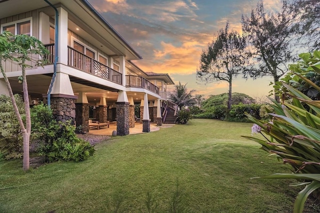 yard at dusk with a patio and a balcony