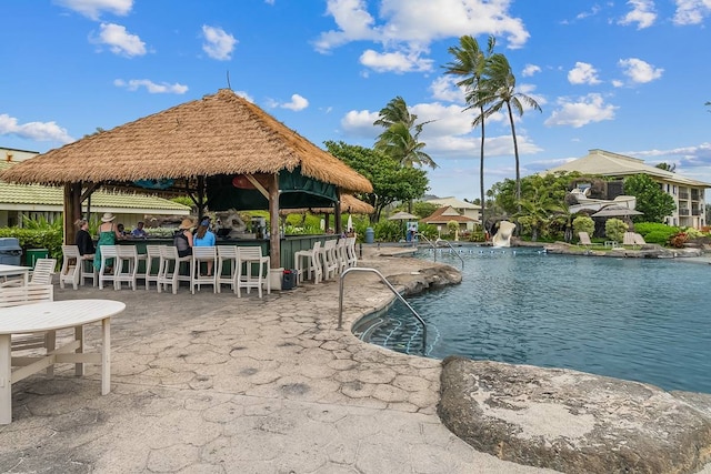 exterior space featuring a swimming pool, a gazebo, and an outdoor bar