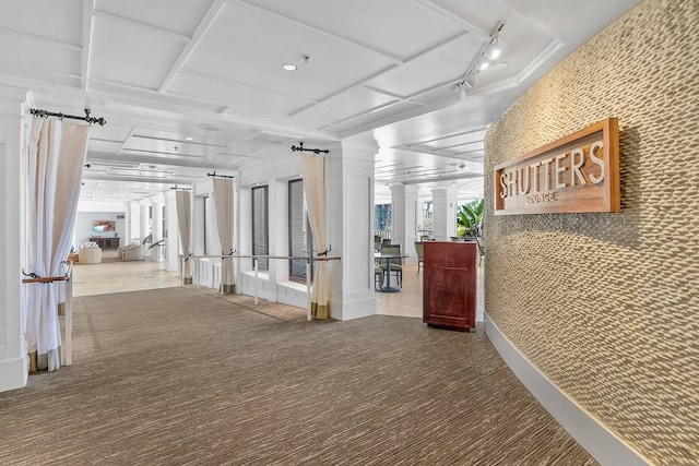 interior space featuring carpet floors, decorative columns, and track lighting