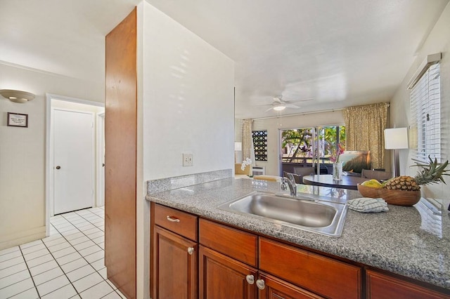 kitchen featuring light tile flooring, dark stone counters, ceiling fan, and sink