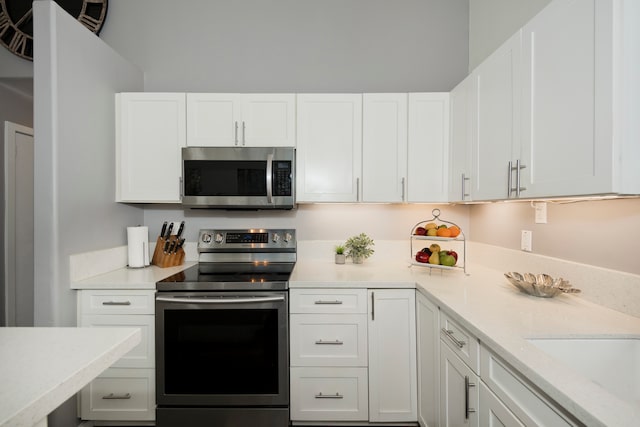 kitchen with white cabinets, appliances with stainless steel finishes, and light stone counters