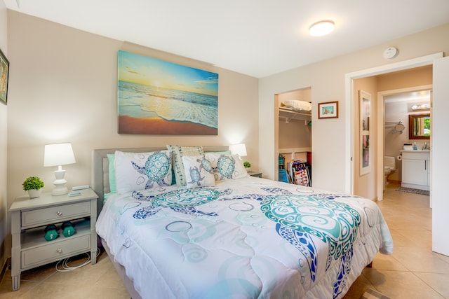 bedroom with a spacious closet, a closet, light tile floors, and ensuite bathroom