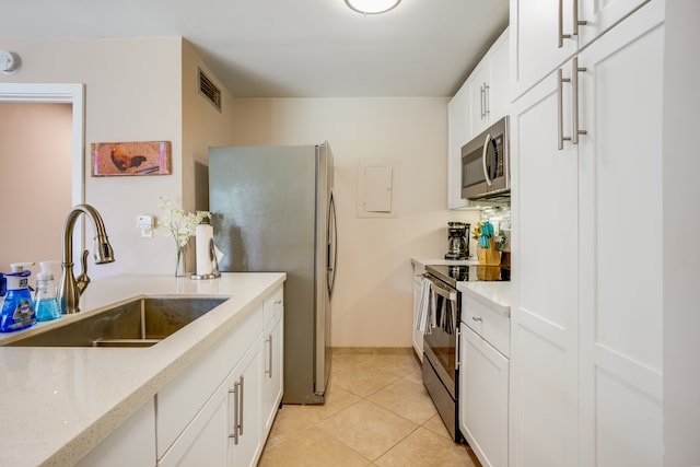 kitchen featuring light stone counters, sink, light tile flooring, white cabinetry, and stainless steel appliances