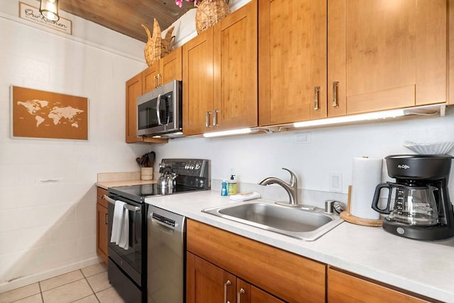 kitchen with appliances with stainless steel finishes, sink, and light tile flooring