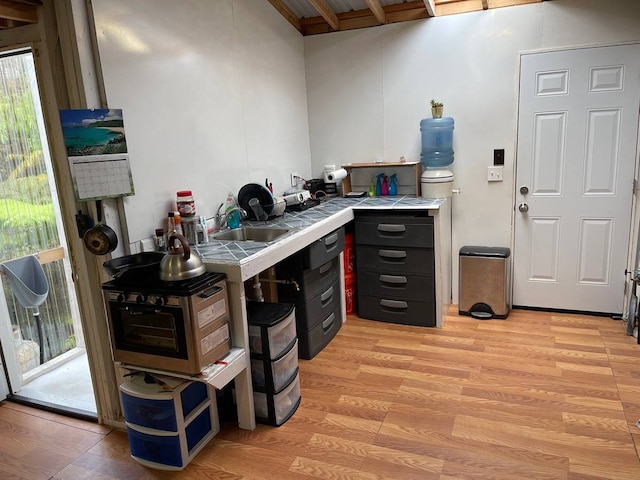 interior space with tile countertops, sink, and light hardwood / wood-style flooring