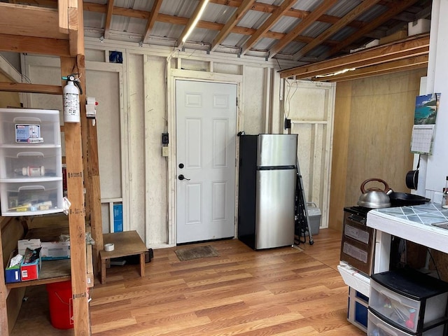 basement featuring stainless steel fridge and light wood-type flooring