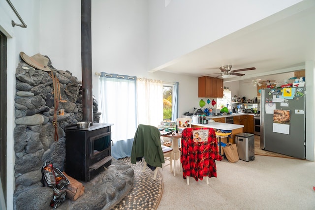 dining room with a wood stove, ceiling fan, and light carpet