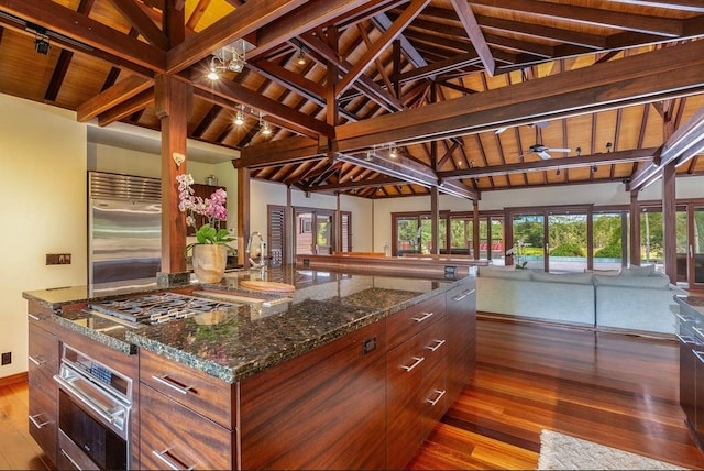 kitchen featuring appliances with stainless steel finishes, a center island, dark stone countertops, and wooden ceiling