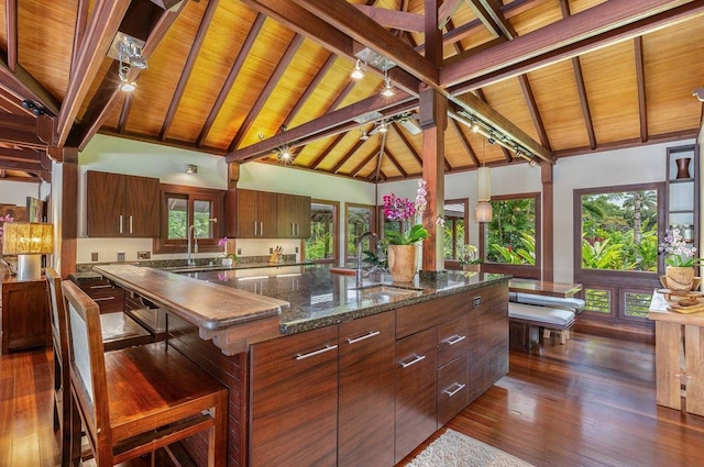 kitchen with wooden ceiling, an island with sink, high vaulted ceiling, sink, and beam ceiling