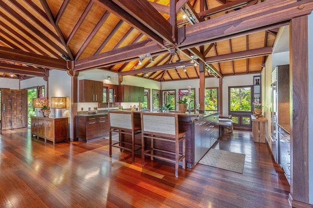 kitchen with dark hardwood / wood-style flooring, wooden ceiling, a kitchen island with sink, high vaulted ceiling, and beam ceiling