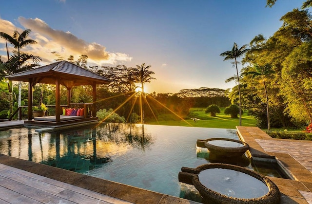 pool at dusk featuring a patio and a gazebo