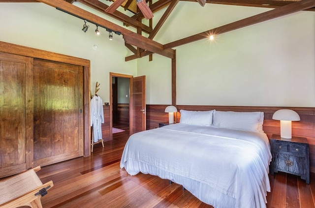 bedroom with high vaulted ceiling, dark wood-type flooring, beam ceiling, and rail lighting