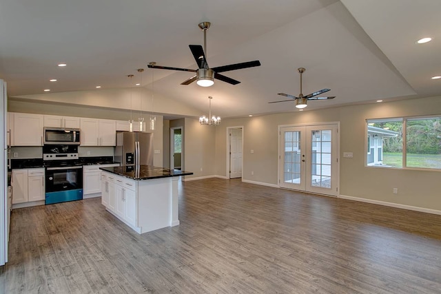 kitchen featuring stainless steel appliances, wood-type flooring, dark stone counters, white cabinetry, and a center island