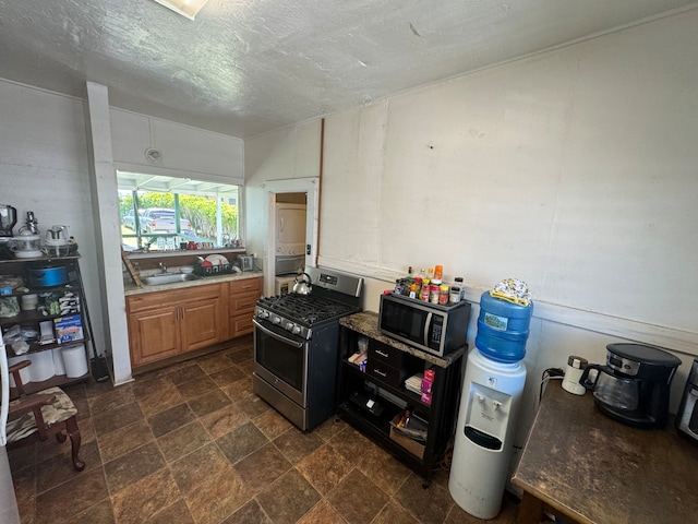 kitchen featuring appliances with stainless steel finishes, a textured ceiling, sink, and dark tile floors