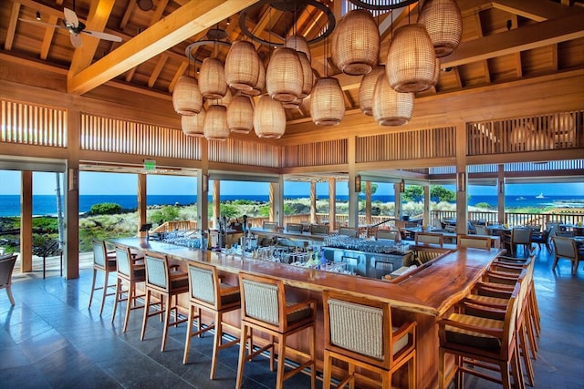 bar with a water view, tile floors, beamed ceiling, wood ceiling, and a high ceiling