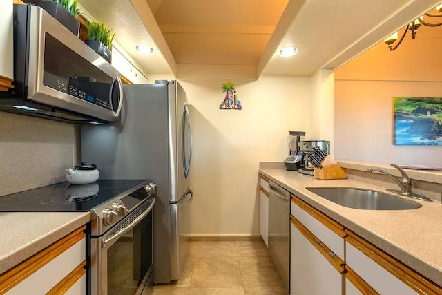 kitchen with appliances with stainless steel finishes, sink, white cabinets, and light tile floors