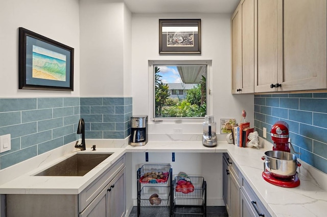 kitchen featuring backsplash, gray cabinetry, sink, and light stone countertops