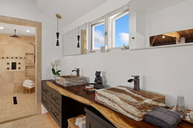 bathroom with tile flooring, vanity, and a tile shower