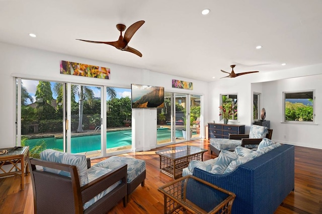 living room featuring ceiling fan, a wealth of natural light, and dark wood-type flooring