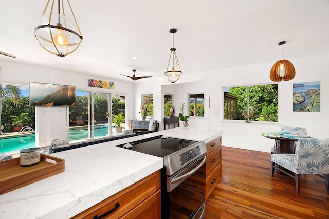 kitchen with hanging light fixtures, electric range, a wealth of natural light, and dark hardwood / wood-style floors