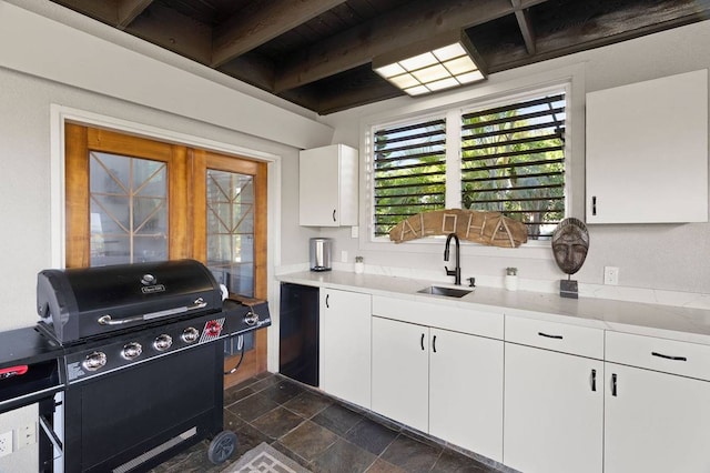 kitchen with dark tile floors, white cabinets, beamed ceiling, sink, and wood ceiling