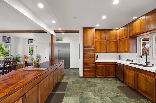 kitchen featuring backsplash, appliances with stainless steel finishes, dark tile flooring, and sink