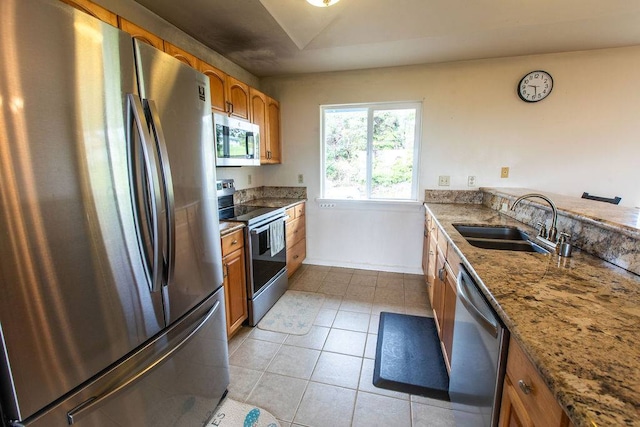 kitchen featuring appliances with stainless steel finishes, sink, light stone countertops, and light tile flooring