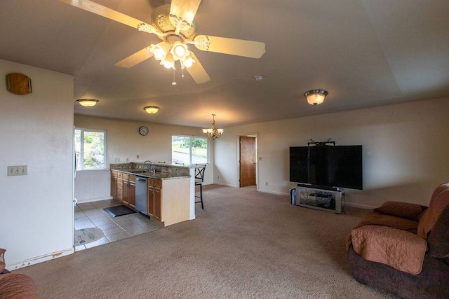 kitchen featuring light tile floors, dishwasher, ceiling fan with notable chandelier, decorative light fixtures, and a kitchen breakfast bar