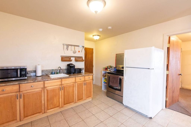 kitchen with appliances with stainless steel finishes, sink, and light tile flooring