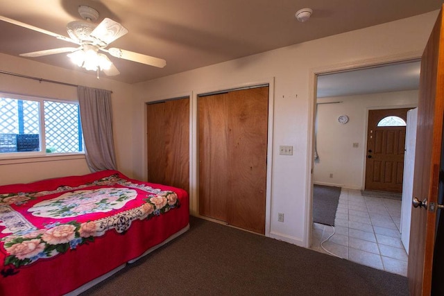 carpeted bedroom with ceiling fan and two closets