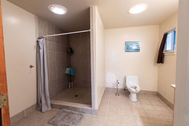 bathroom featuring curtained shower, toilet, and tile flooring