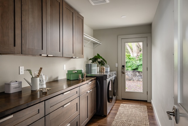 laundry area with washing machine and clothes dryer, cabinets, and hardwood / wood-style floors