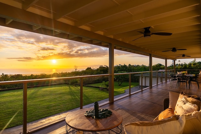 deck at dusk featuring ceiling fan and a lawn